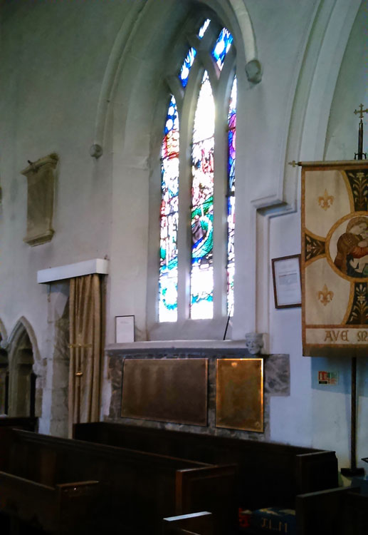 Beneath this memorial window are two bronze metal tablets